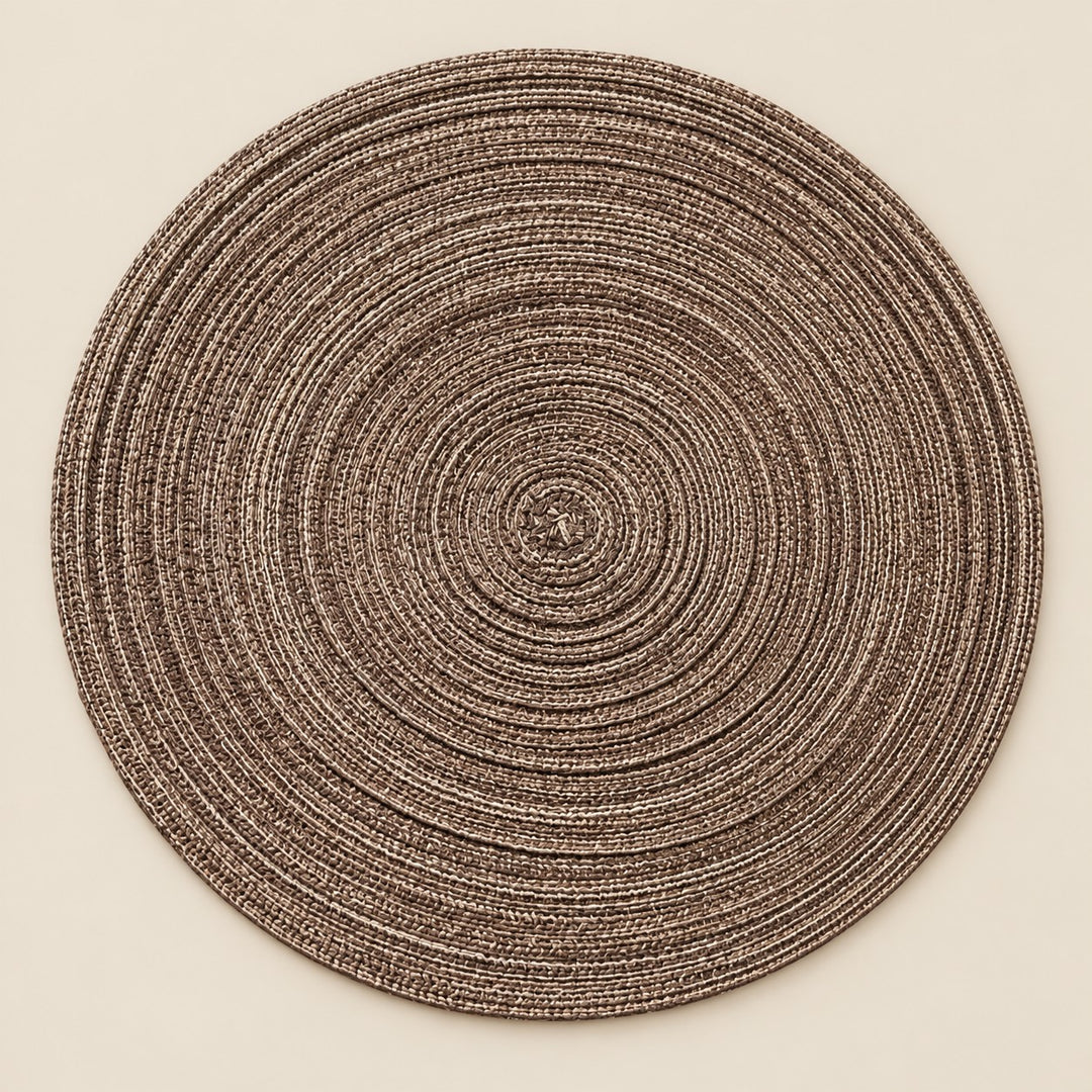 Single brown round woven polyester placemat centered on a softly tinted warm beige studio background.