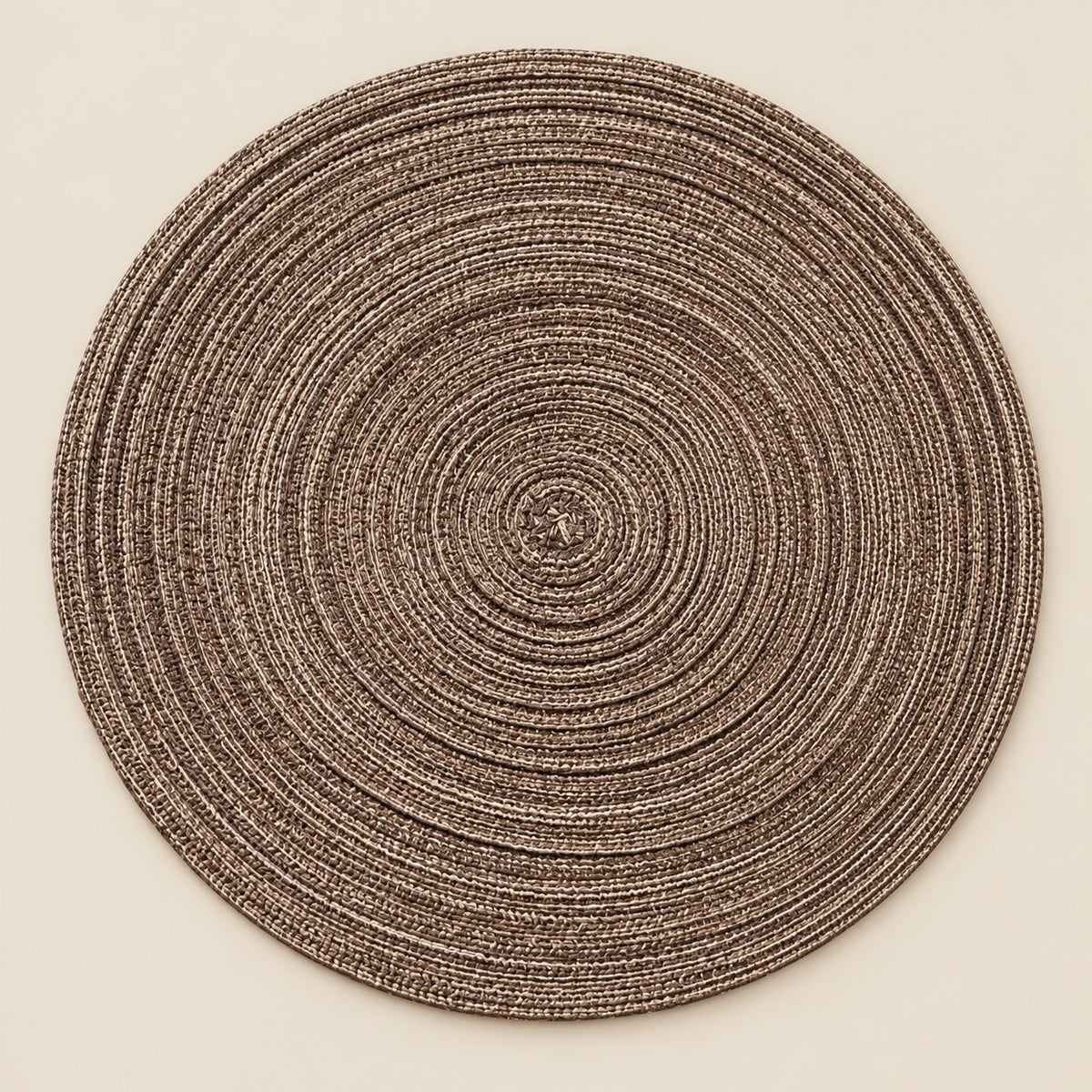 Single brown round woven polyester placemat centered on a softly tinted warm beige studio background.