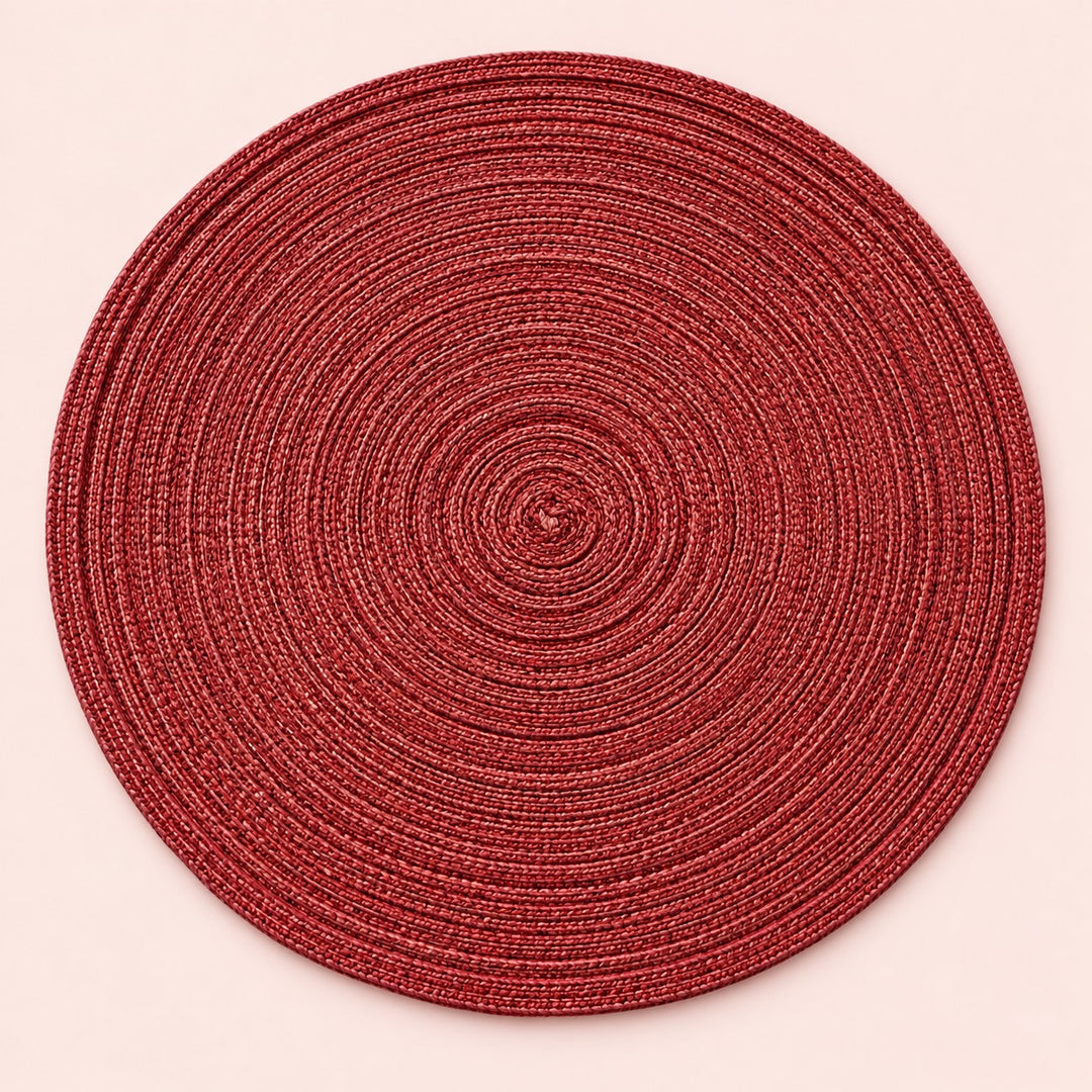 Single red round woven polyester placemat centered on a softly tinted blush studio background.