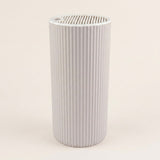 A light gray ribbed cylindrical filter cartridge with a slotted top opening, shown against a solid off-white background.