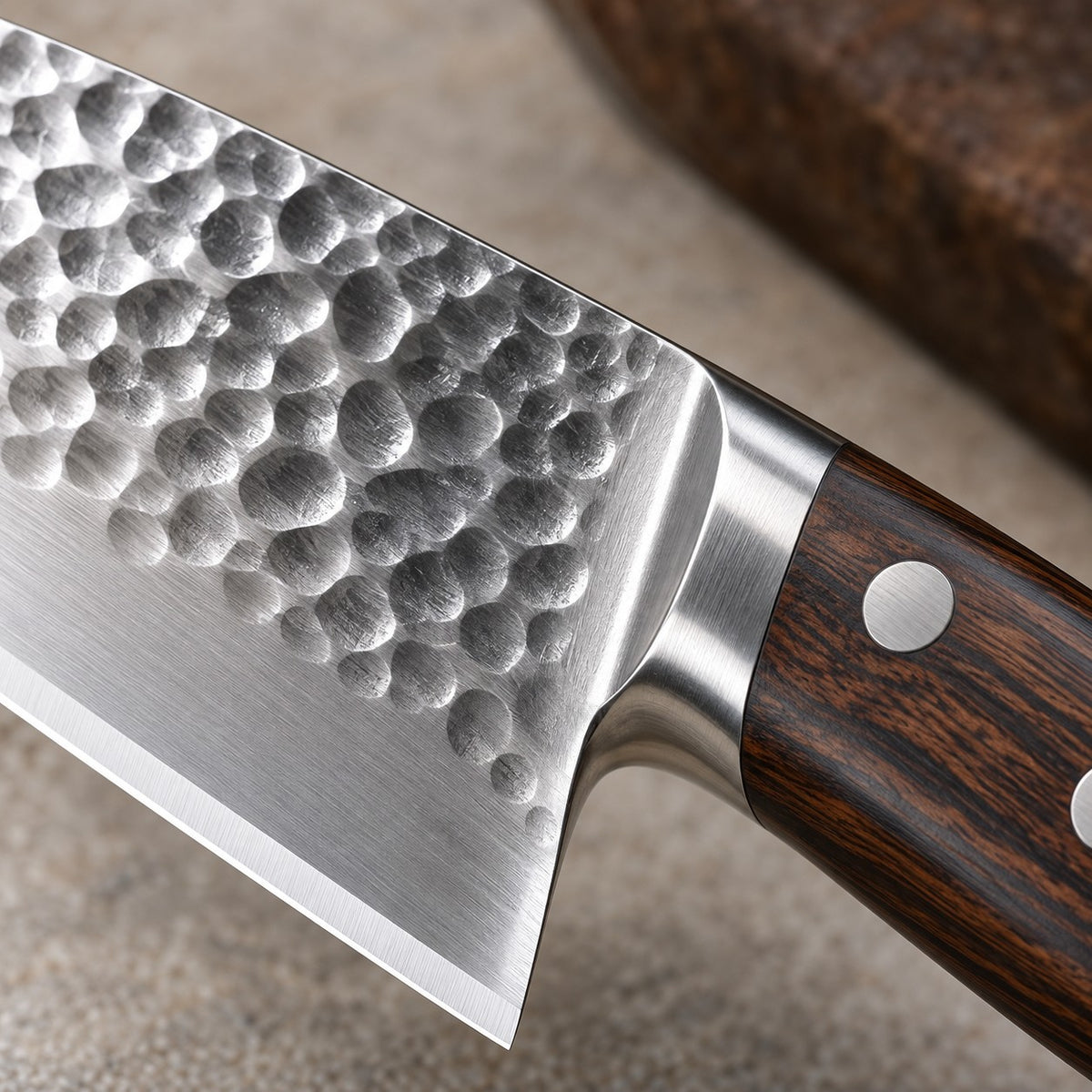 A close-up of the 15-piece hammered kitchen knife set shows a dimpled stainless blade and Pakka wood handle.