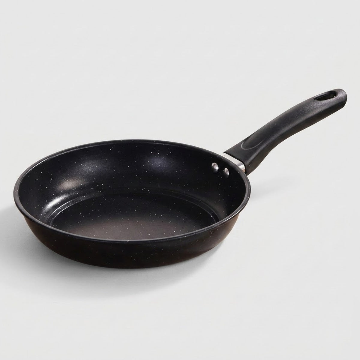 A black non-stick frying pan with a textured interior and a red circular heat indicator in the bottom center, featuring a black handle with a silver metal connector, shown on a plain white background.