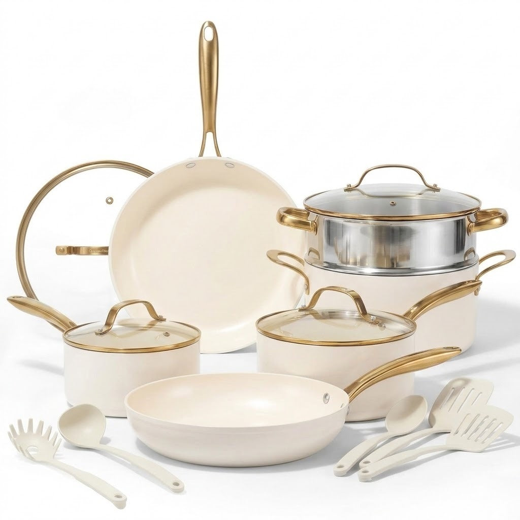 An 11-piece ceramic nonstick cookware set in cream with gold-tone metal handles and trim, shown with stainless steel steamer insert and white silicone utensils on a white background.