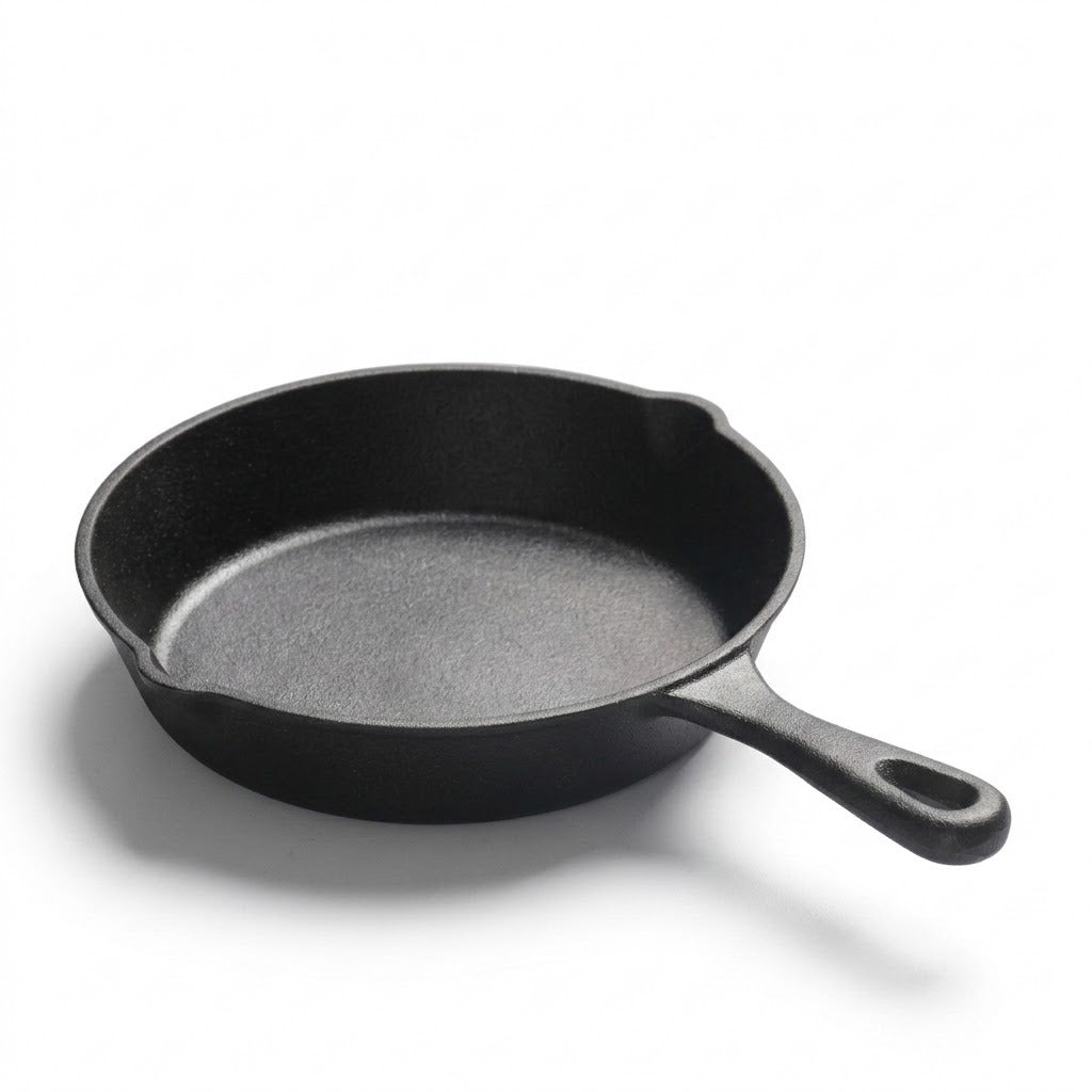 A classic black cast iron skillet with a textured interior and a single loop handle, photographed on a clean white background with a soft shadow.