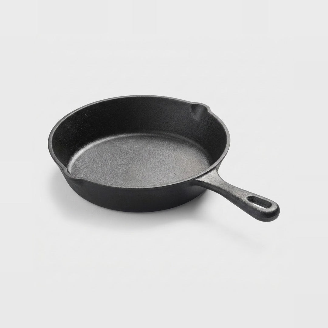 A classic black cast iron skillet with a textured interior and a single loop handle, photographed on a clean white background.