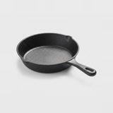 A classic black cast iron skillet with a textured interior and a single loop handle, photographed on a clean white background.