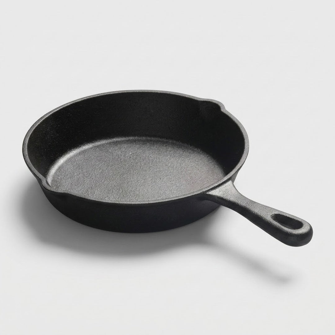 A classic black cast iron skillet with a textured interior and a loop handle, photographed on a clean light gray background.