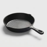 A classic black cast iron skillet with a textured interior and a loop handle, photographed on a clean light gray background.