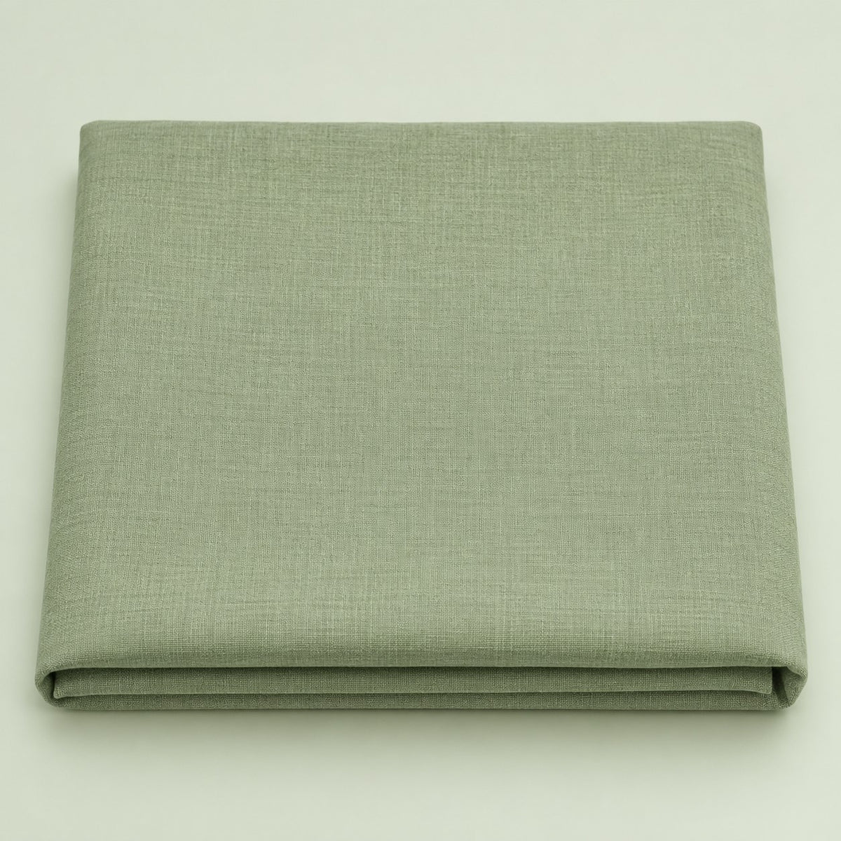 Folded sage green polyester tablecloth centered on a soft sage studio background.
