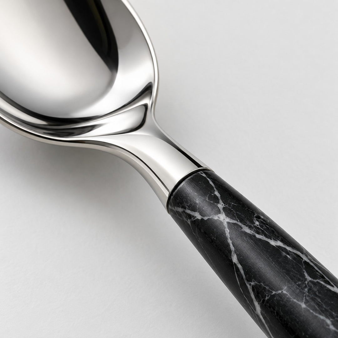 Close-up of polished stainless steel and the black imitation-wood handle with white veining.