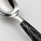 Close-up of polished stainless steel and the black imitation-wood handle with white veining.