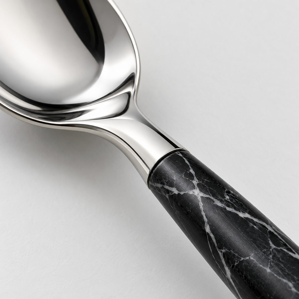 Close-up of polished stainless steel and the black imitation-wood handle with white veining.