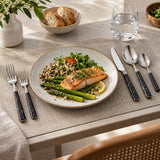 Black and silver five-piece flatware set arranged with a plated meal for a coordinated place setting.