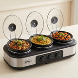 A three-compartment electric skillet set with clear glass lids, shown with food cooked in each compartment on a light beige background.