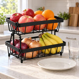 Black Two-Tier Produce Basket holds produce beside a dinner plate and drinking glass.