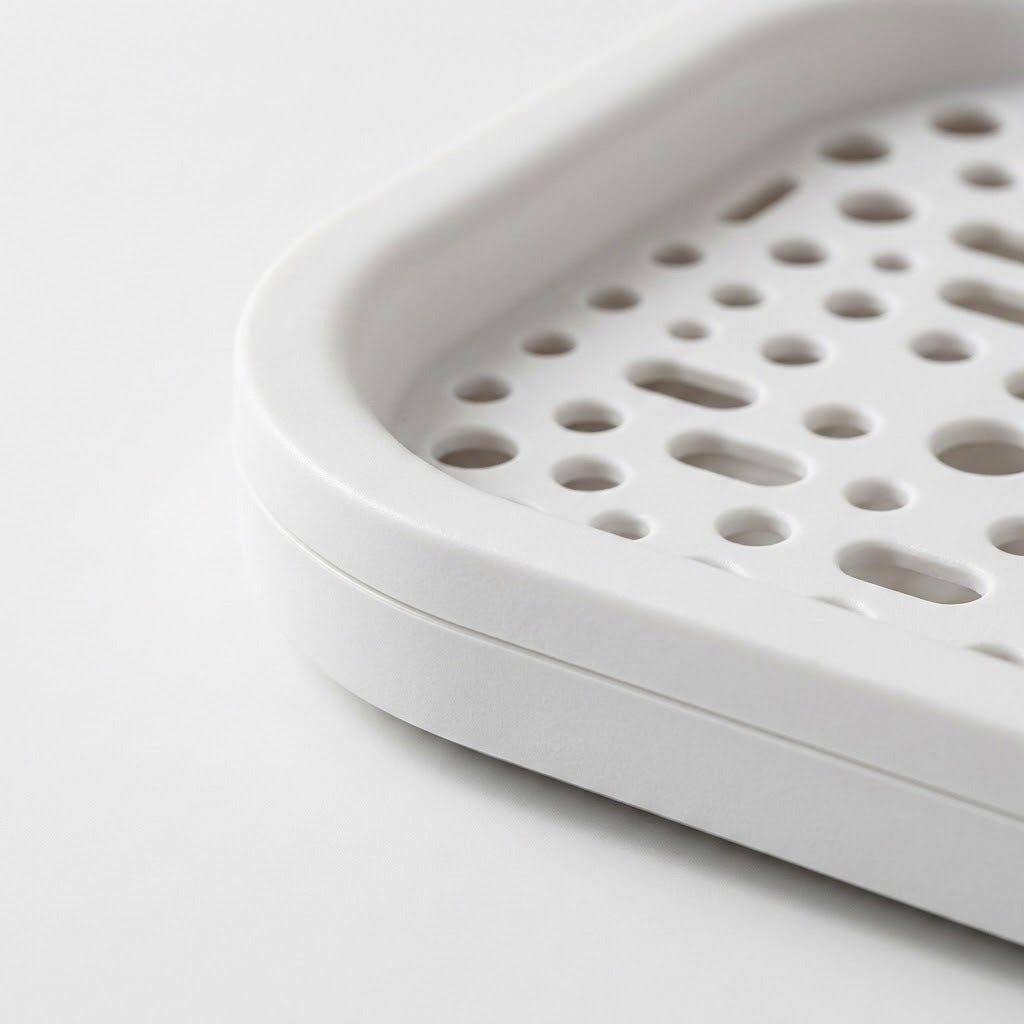 Close-up of a white plastic tray or basket with a perforated drainage design, shown on a clean white background.