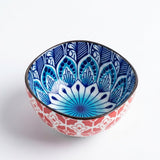 A hand-painted ceramic bowl with a blue and white mandala pattern on the inside and a coral red and white geometric pattern on the outside, shown on a white background.