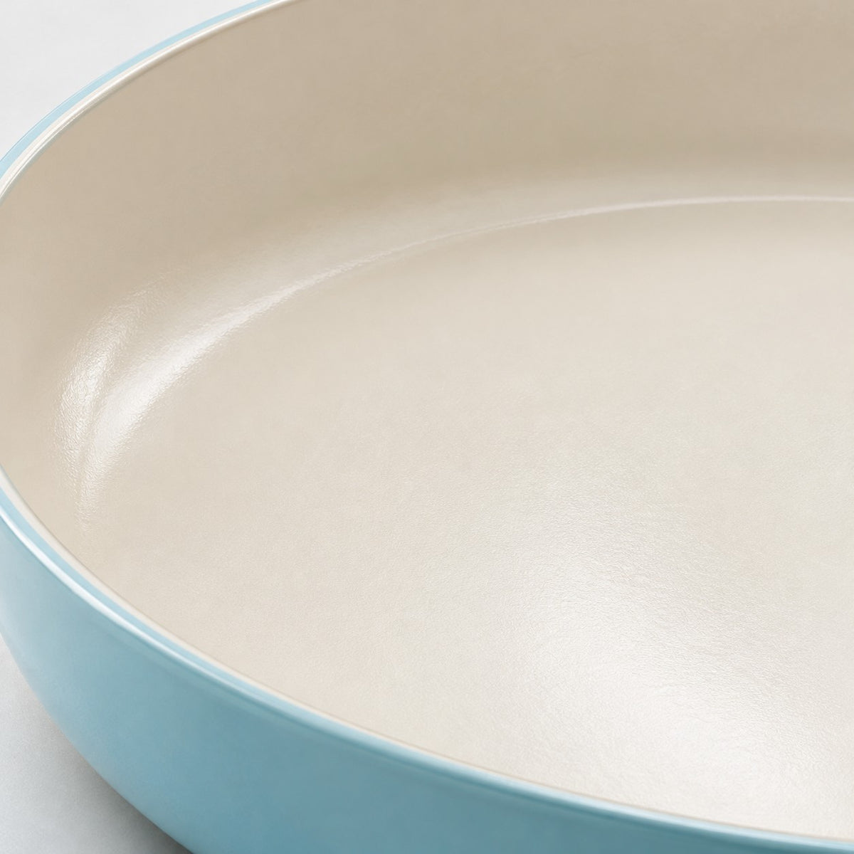 Ceramic Glaze Nonstick Frying Pan close-up showing its smooth ivory glaze and aqua rim.