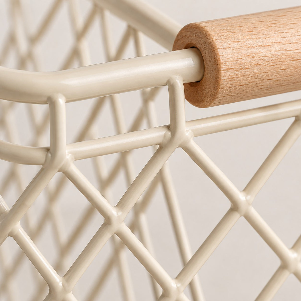 Close view of the beige iron mesh, welded joints and natural wood grip on the wire basket.