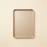 A rectangular metal baking sheet with rounded corners, shown from a top-down view on a solid, warm cream-colored background.