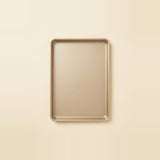 A rectangular metal baking pan with raised edges, shown from above on a plain warm cream background.