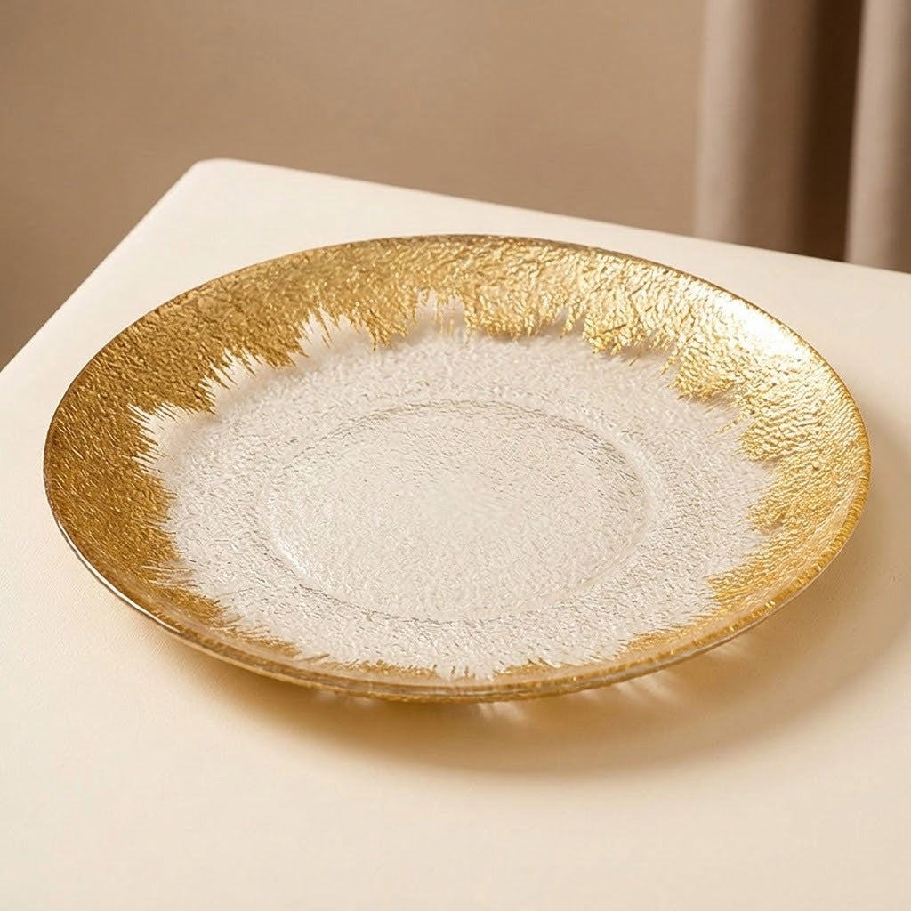 A round ceramic plate with a textured gold outer rim and a matte white center, displayed on a light beige surface.