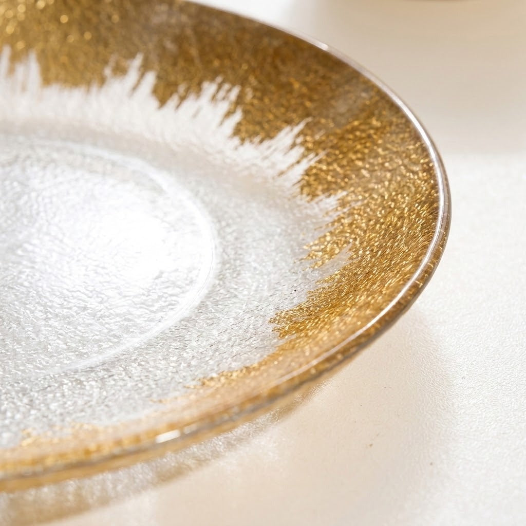 A close-up of a clear glass plate with a textured, hammered finish and a decorative metallic gold border.