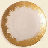 A round white plate with a textured, metallic gold abstract brushstroke border, shown from a top-down view on a light cream background.