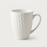 A white ceramic mug with a textured, wavy diamond pattern and a curved handle, shown on a clean, light off-white background.