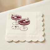A square cream-colored paper napkin with scalloped edges, printed with a burgundy illustration of two dessert glasses and the text 'I <heart> u 09.29.