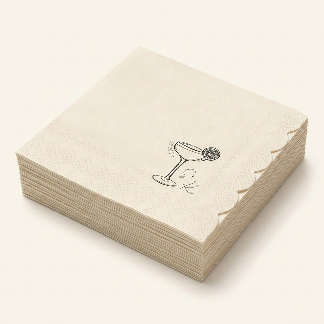 A stack of square cream-colored paper napkins with scalloped edges, featuring a black line art illustration of a martini glass with a lemon wheel garnish and the text 'SIR RICHARD' printed on the top napkin.