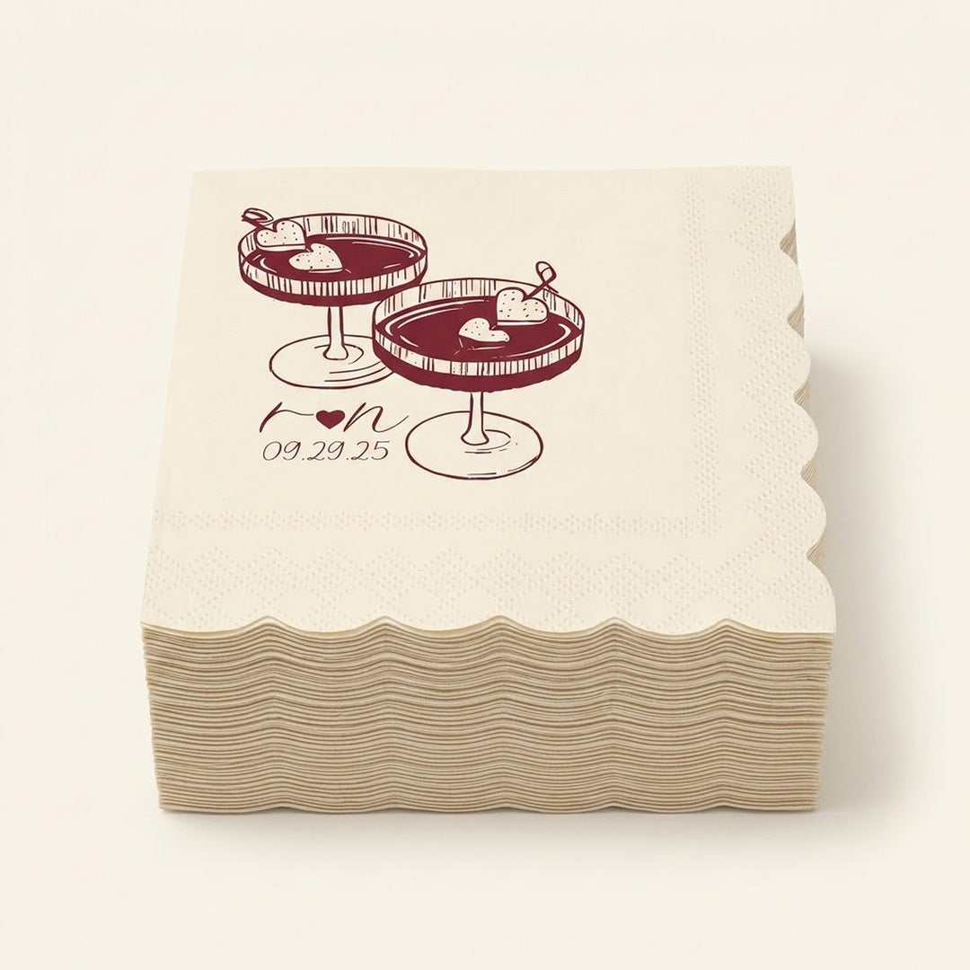 A stack of square paper napkins with scalloped edges, printed with an illustration of two dessert cocktails and the date '09.29.