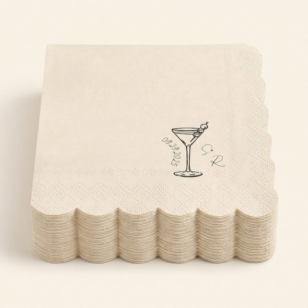 A stack of off-white paper cocktail napkins with scalloped edges, each printed with a black martini glass illustration and the words 'Sour' and 'Straw'.