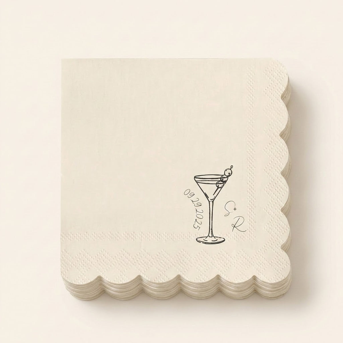 A stack of square off-white paper napkins with scalloped edges, featuring a black line art illustration of a martini glass with an olive, the date '09.28.