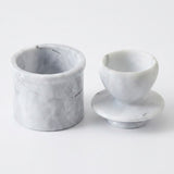A pair of small round marble containers or cups, one cylindrical and one rounded with a matching base, shown on a clean white background.