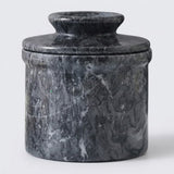 A cylindrical stone lidded container or vase made of dark gray and black marble with natural white veining, photographed against a light gray background.