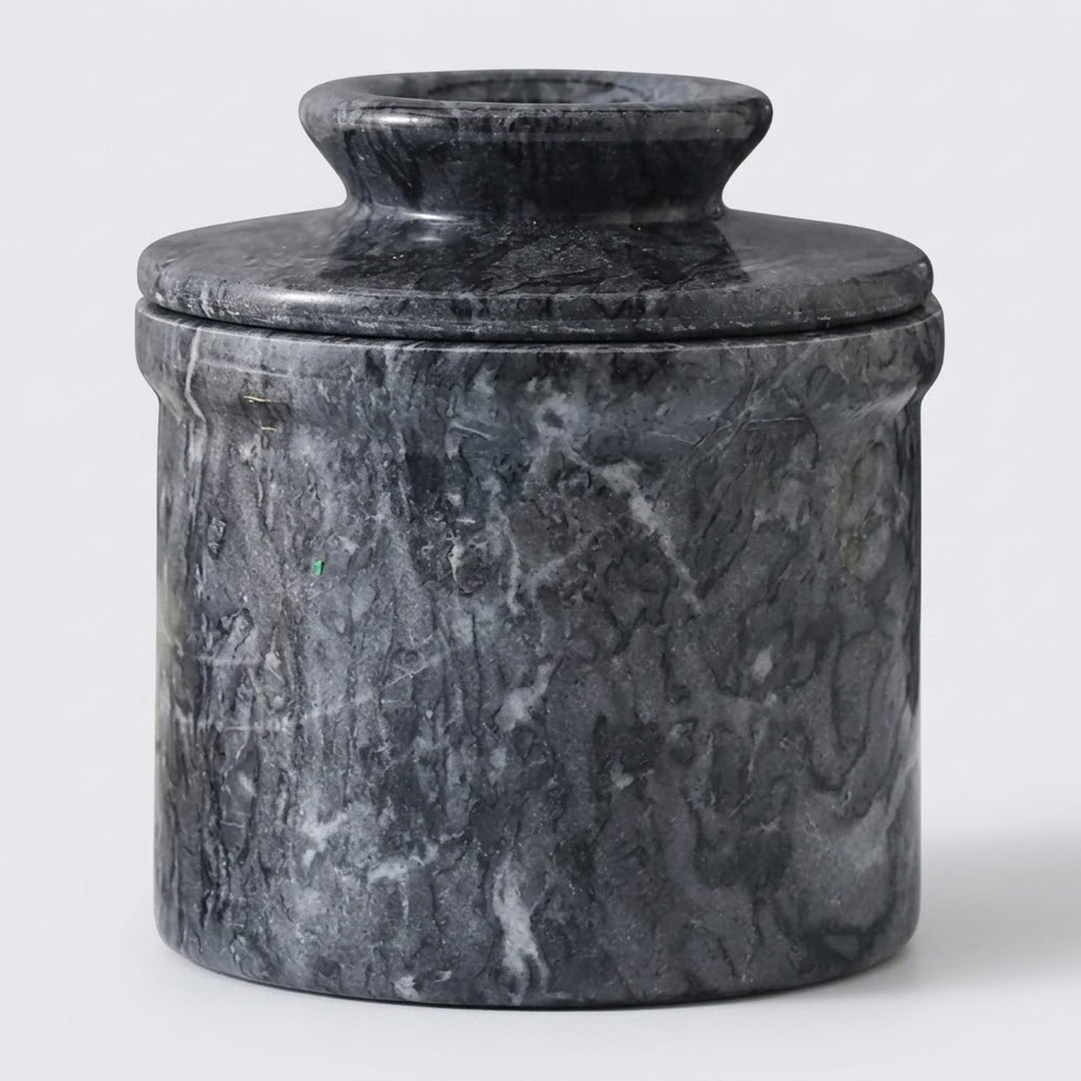 A cylindrical stone lidded container or vase made of dark gray and black marble with natural white veining, photographed against a light gray background.