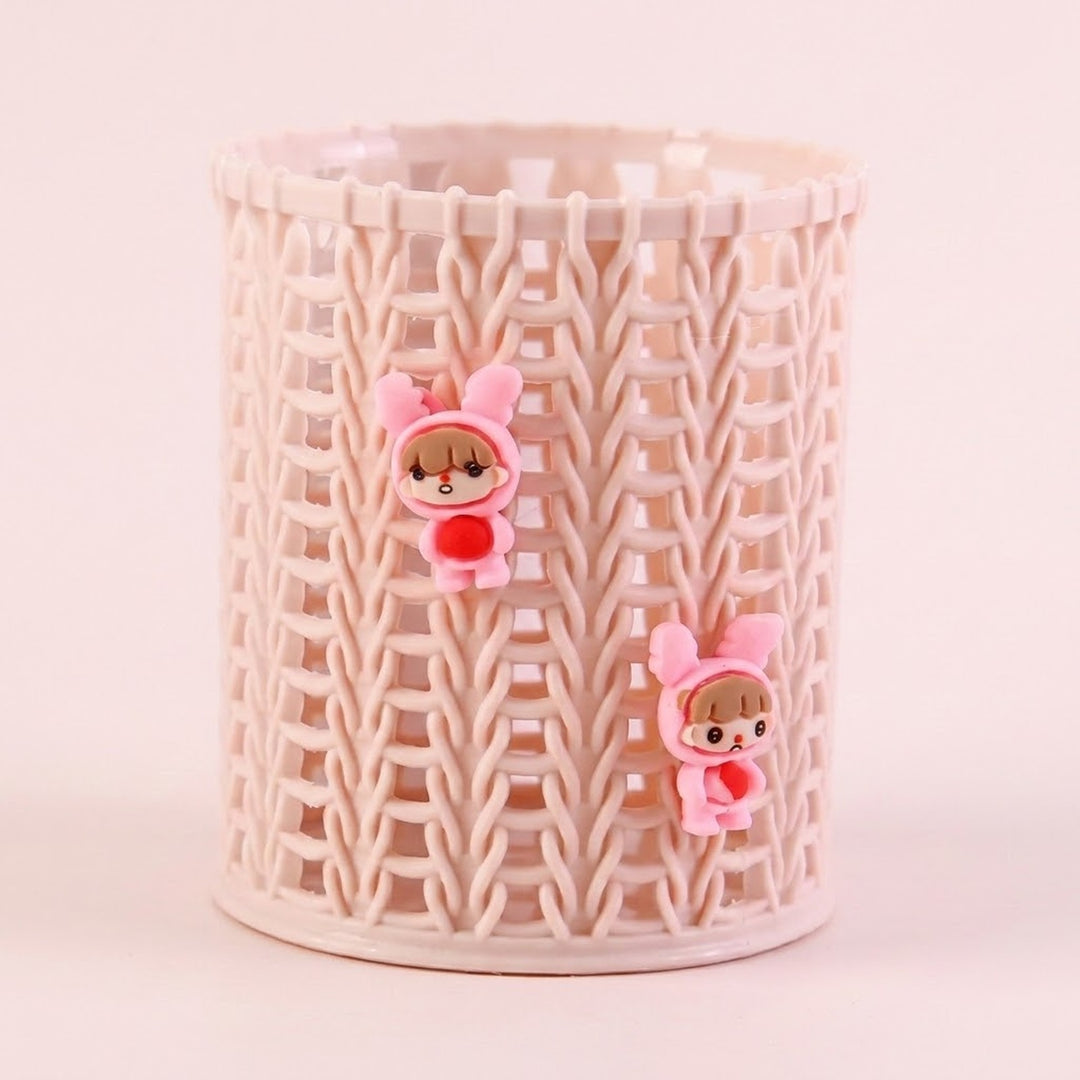 A cylindrical plastic basket with a cream-colored interlocking wavy pattern, decorated with two small pink bunny-ear character charms holding red hearts.