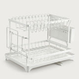 A white two-tier metal dish rack with a sink-mounted cup holder and hanging utensil hooks, shown on a light gray background.