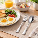 Stainless steel spoon and fork set ready beside breakfast in a bright home kitchen.