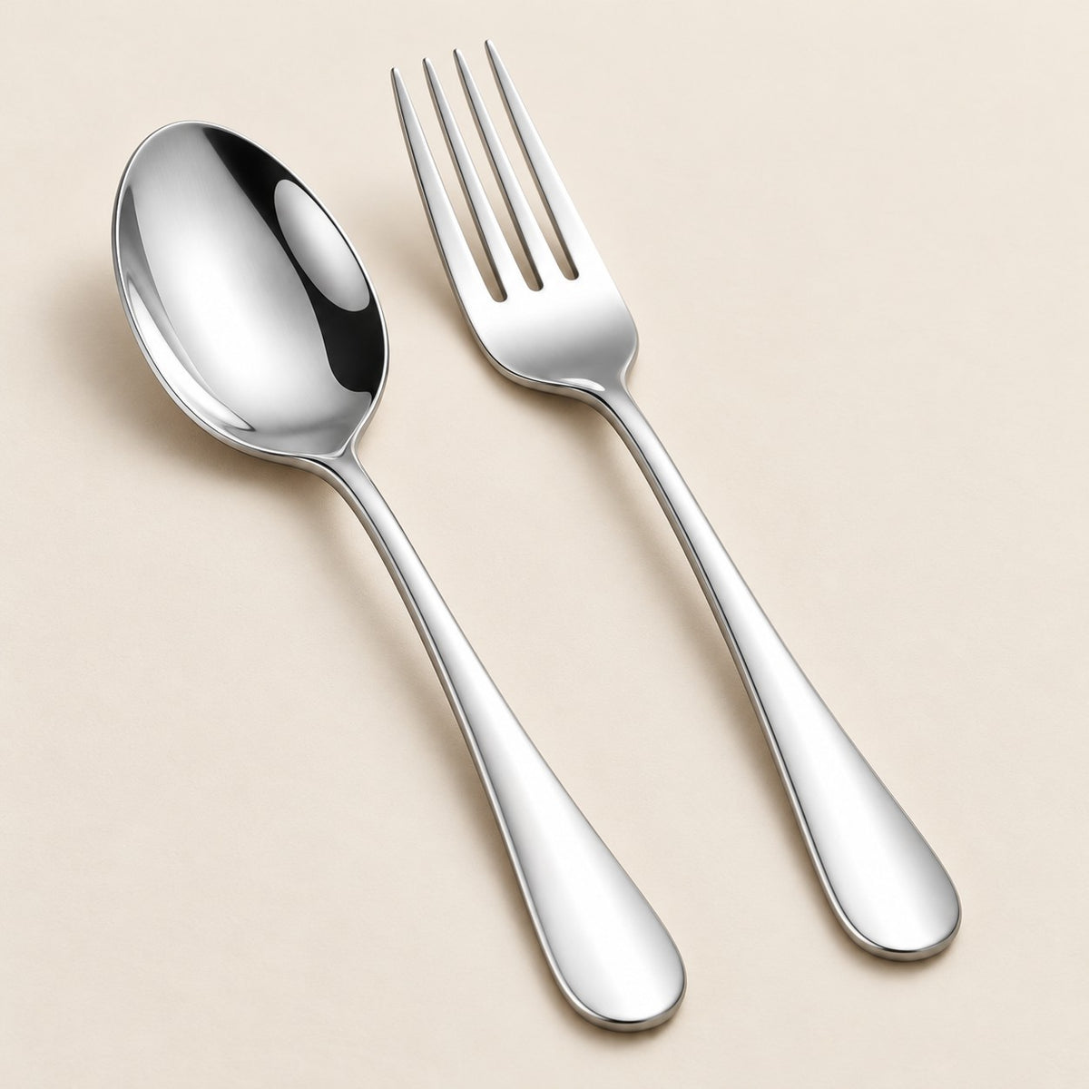 Polished stainless steel spoon and fork show a simple coordinated finish on a neutral surface.