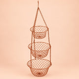 Copper Three Tier Hanging Fruit Basket hangs assembled against a soft peach studio background.