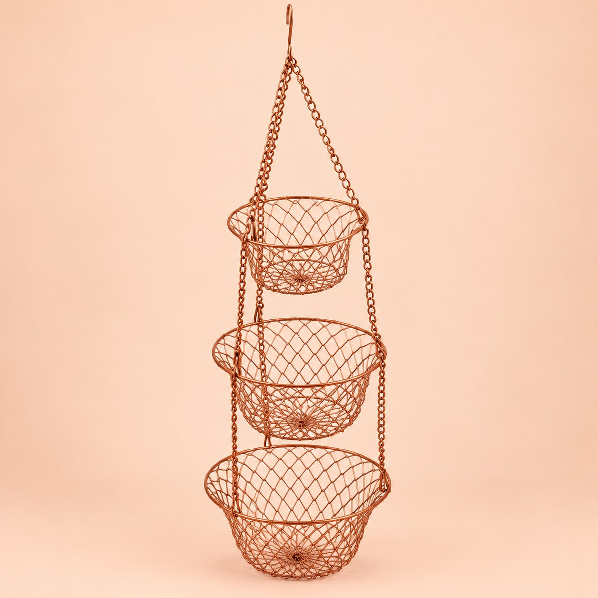 Copper Three Tier Hanging Fruit Basket hangs assembled against a soft peach studio background.
