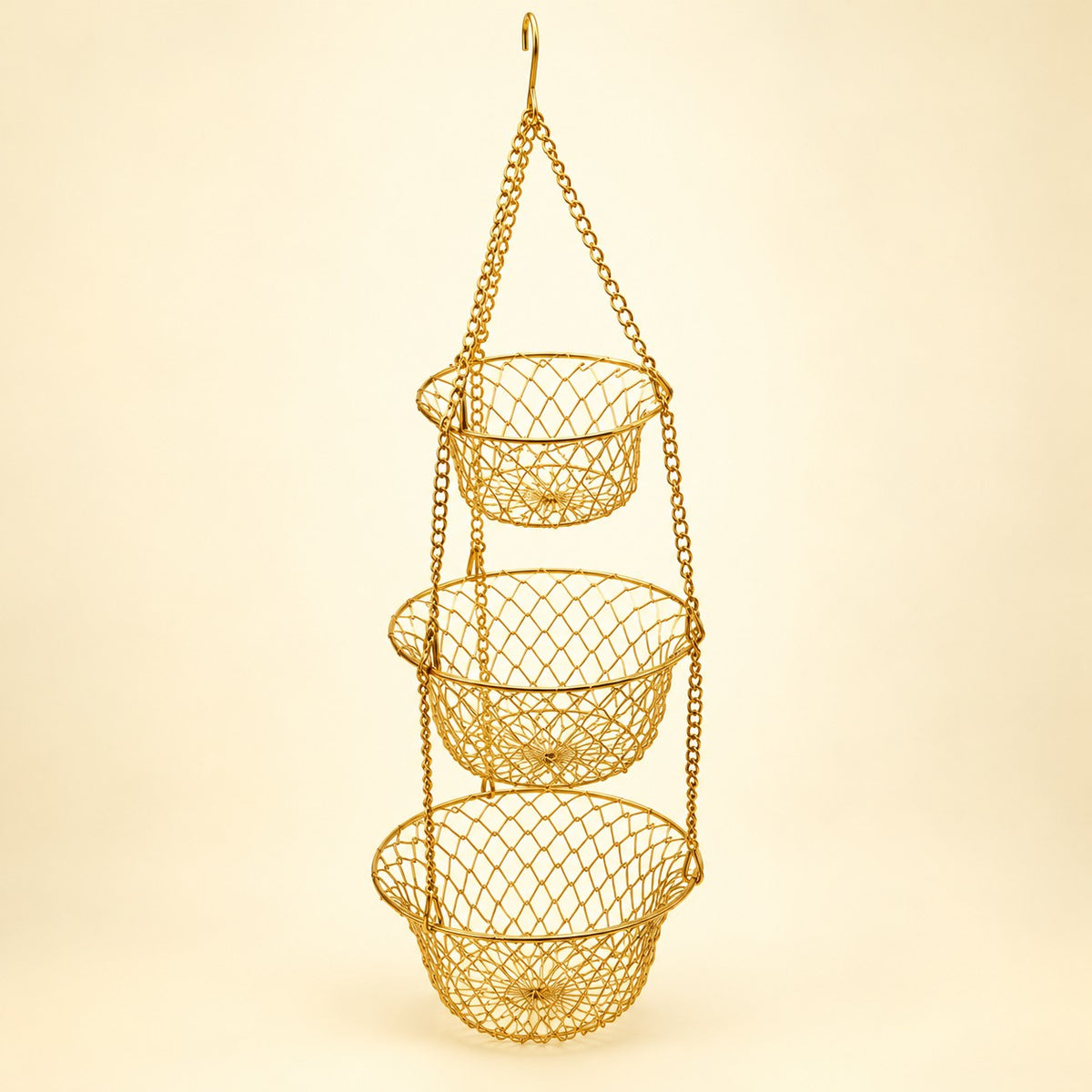 Gold Three Tier Hanging Fruit Basket hangs assembled against a pale gold studio background.