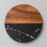 Black Round coaster pairs warm acacia wood with dark marble on a light studio backdrop.