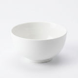 A minimalist white ceramic bowl with a smooth, matte finish, photographed on a seamless white background.