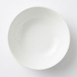 A minimalist white ceramic bowl photographed from directly above on a clean white background.