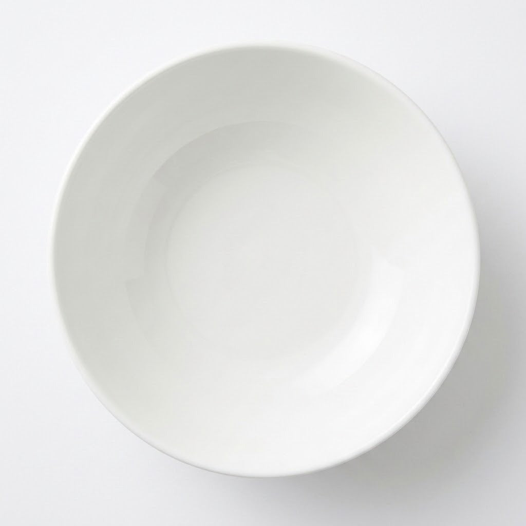 A minimalist white ceramic bowl photographed from directly above on a clean white background.