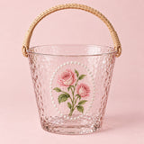 Rose floral hammered glass ice bucket with woven handle on a blush studio backdrop.