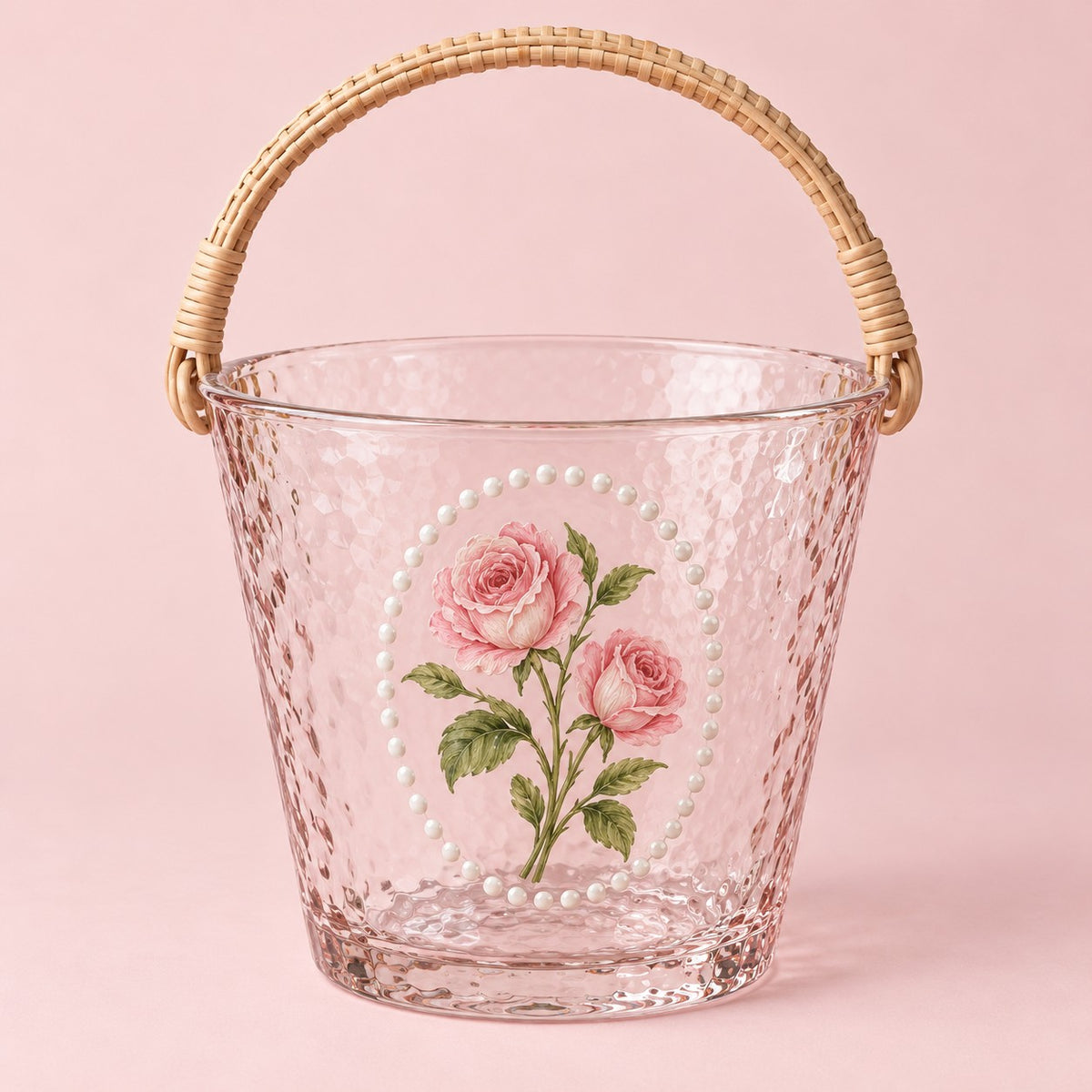 Rose floral hammered glass ice bucket with woven handle on a blush studio backdrop.